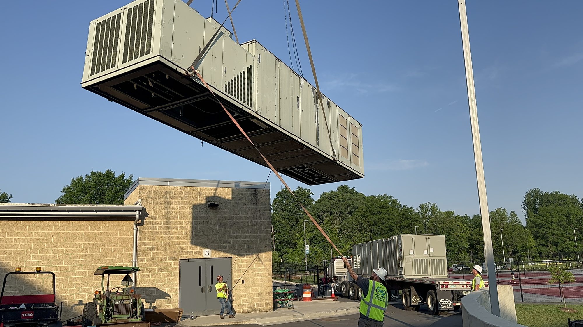 Crane removing an old rooftop unit during replacement
